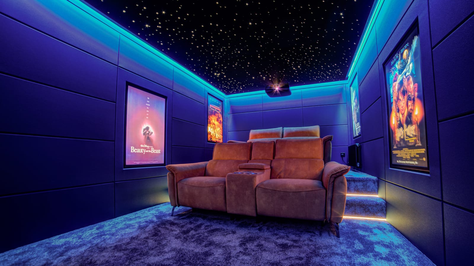Home cinema with padded blue acoustic wall panels, a fibre-optic starlight ceiling and a tan leather recliner sofa, lit by concealed LEDs