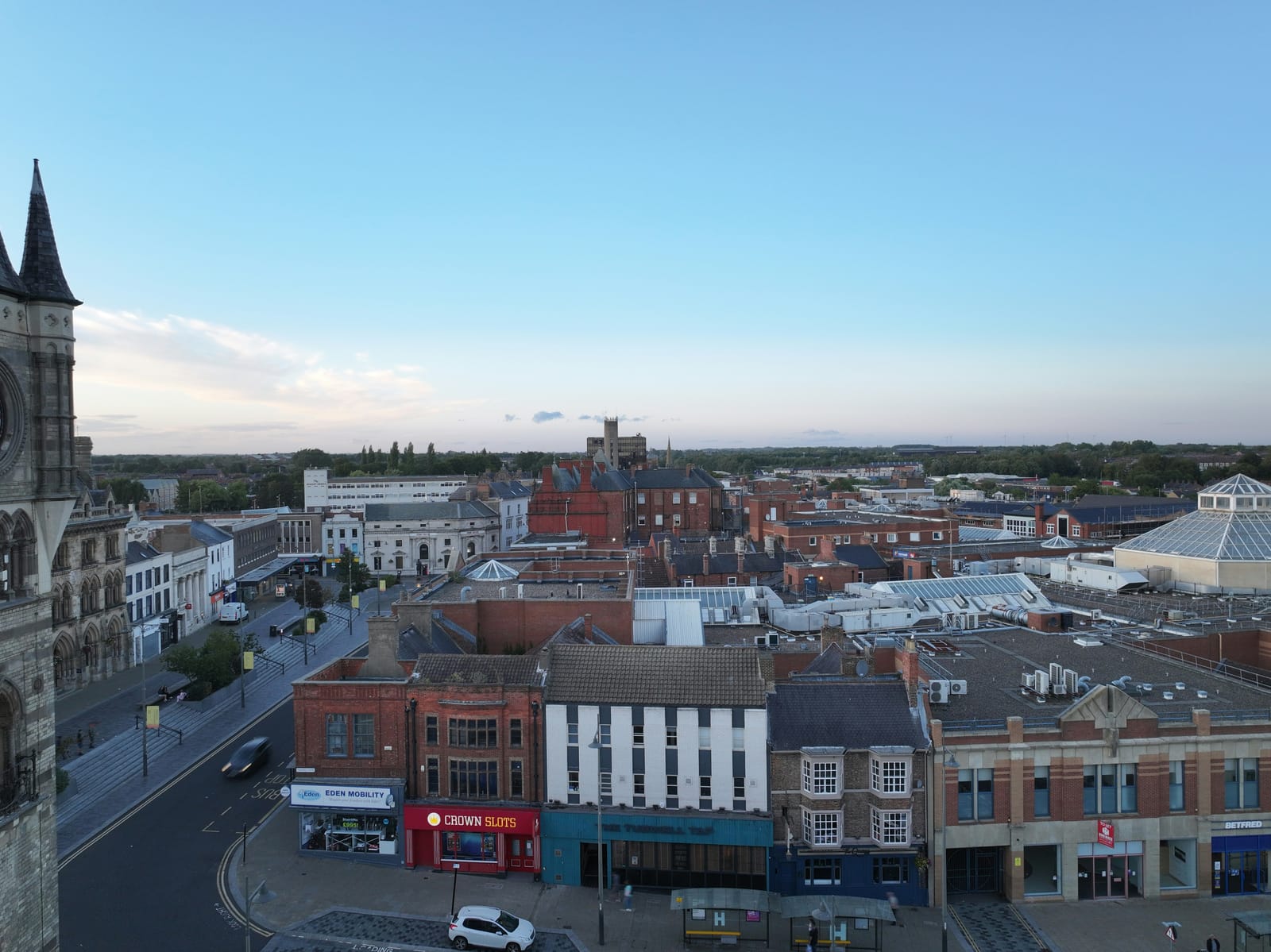 A rooftop view across Darlington town centre at dusk, the church spire on the left and the covered market beyond