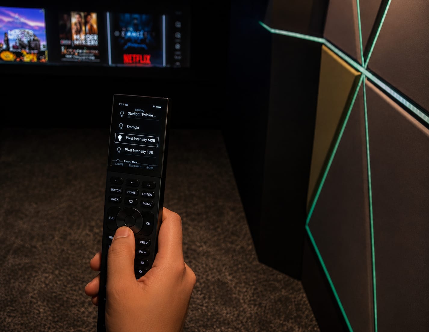 Home cinema installation by Acoustic Pixel: a hand holding a control remote, choosing a starlight lighting scene in a darkened cinema room