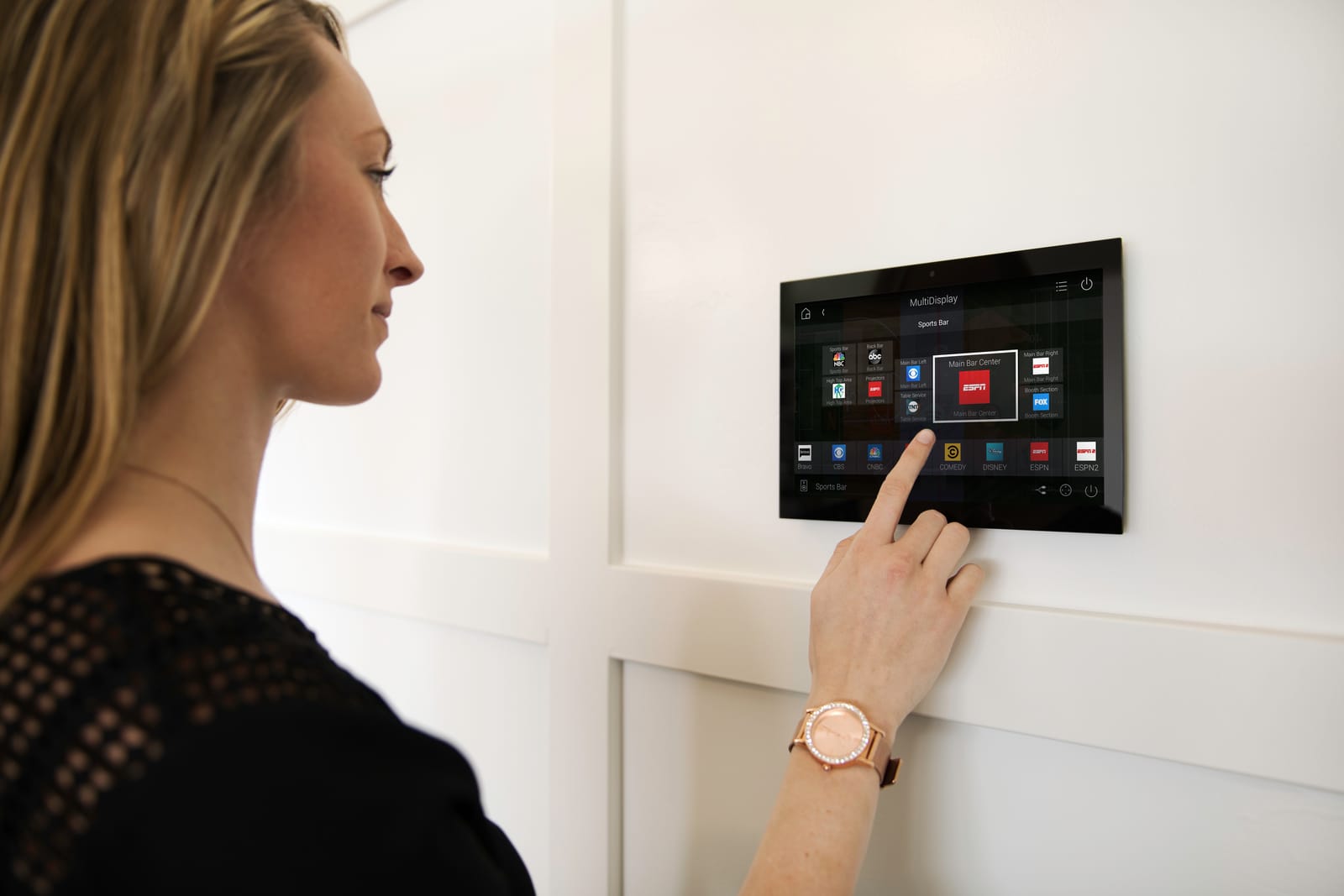 A wall-mounted touchscreen panel being used to choose what plays on each screen in the house